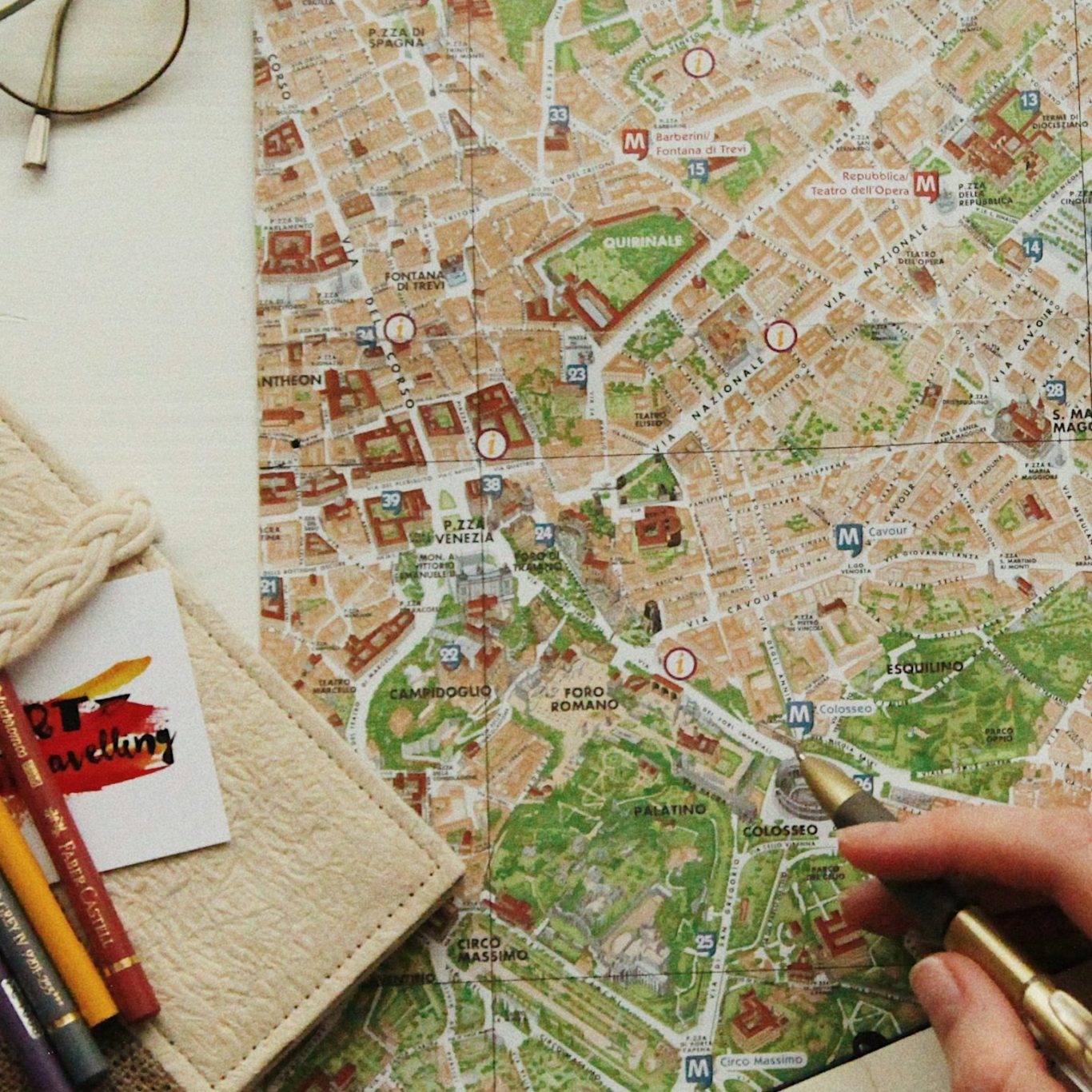 Hand holding a pen over a detailed city map with various colorful markings.